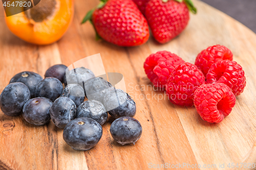 Image of Wooden board with fresh organic fruit and berries