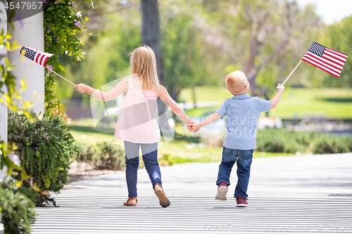 Image of Young Sister and Brother Holding Hands and Waving American Flags