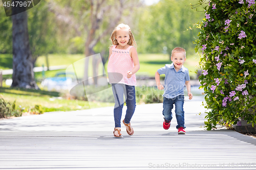 Image of Young Sister and Brother Having Fun Running At The Park