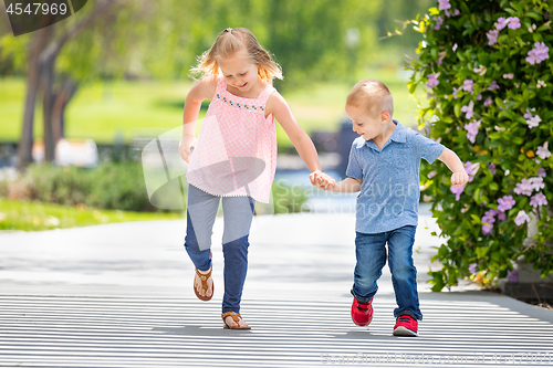 Image of Young Sister and Brother Holding Hands And Running At The Park