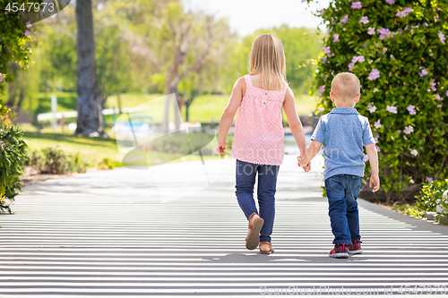 Image of Young Sister and Brother Holding Hands And Walking At The Park