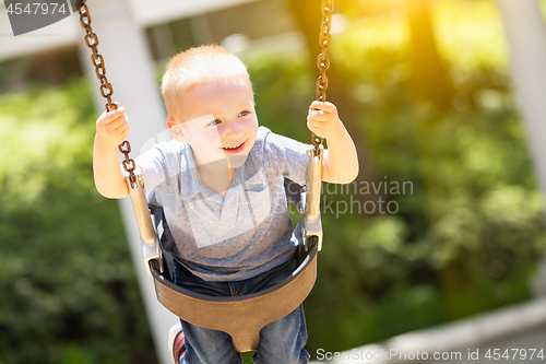 Image of Happy Young Boy Having Fun On The Swings At The Playground