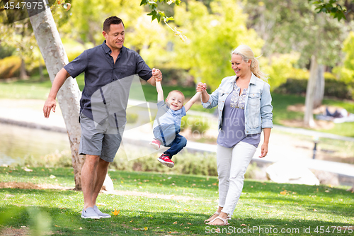 Image of Young Mother and Father Swingging Their Son At The Park