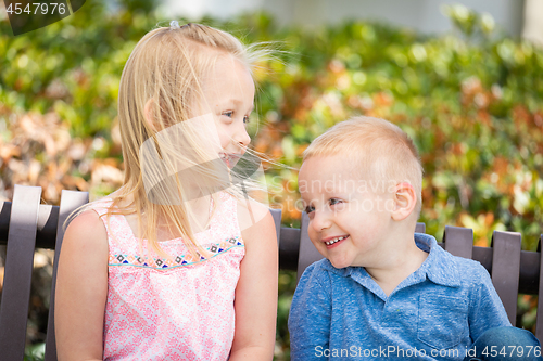 Image of Young Sister and Brother Having Fun On The Bench At The Park