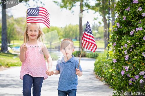 Image of Young Sister and Brother Waving American Flags At The Park