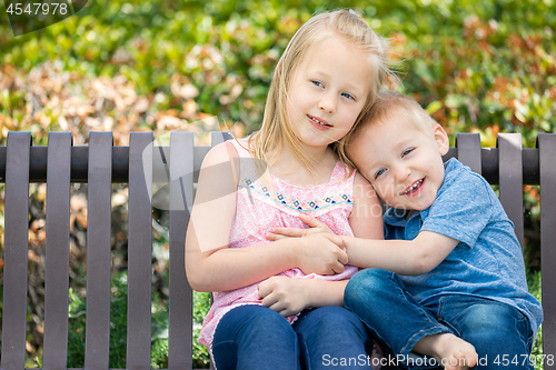 Image of Young Sister and Brother Having Fun On The Bench At The Park