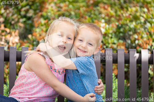 Image of Young Sister and Brother Having Fun On The Bench At The Park