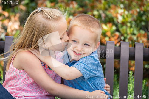 Image of Young Sister and Brother Having Fun On The Bench At The Park