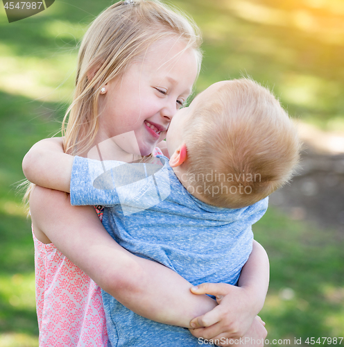 Image of Young Brother and Sister Hugging At The Park