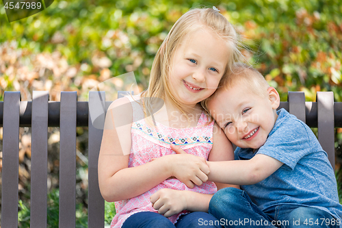 Image of Young Sister and Brother Having Fun On The Bench At The Park