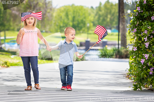 Image of Young Sister and Brother Waving American Flags At The Park