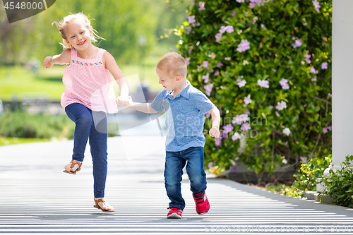 Image of Young Sister and Brother Holding Hands And Running At The Park