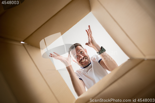 Image of Man unpacking and opening carton box and looking inside