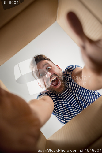 Image of Man unpacking and opening carton box and looking inside