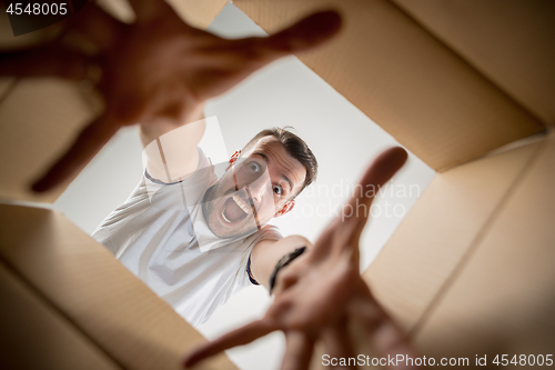 Image of Man unpacking and opening carton box and looking inside