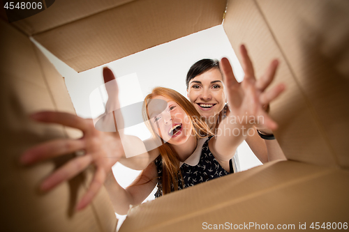 Image of mom and daughter unpacking and opening carton box and looking inside