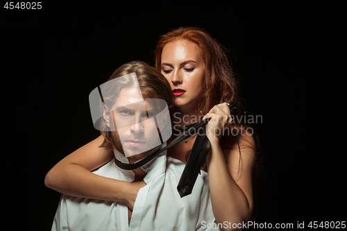 Image of Real passion. Beautiful young loving couple bonding to each other while both standing against black studio walls