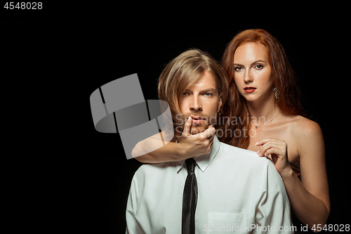 Image of Real passion. Beautiful young loving couple bonding to each other while both standing against black studio walls