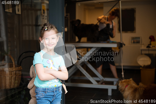 Image of little cute girl standing in front of beauty salon for animals