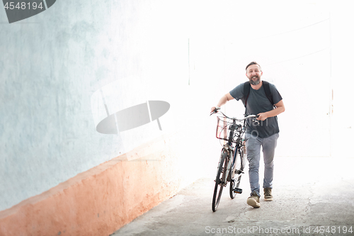 Image of hipster man with a backpack pushing a retro bicycle