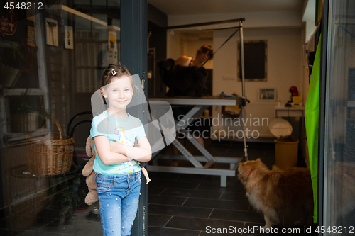 Image of little cute girl standing in front of beauty salon for animals