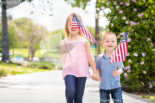 Image of Young Sister and Brother Waving American Flags At The Park