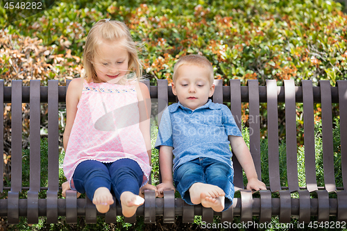 Image of Young Sister and Brother Having Fun On The Bench At The Park