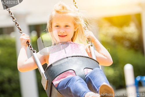 Image of Pretty Young Girl Having Fun On The Swings At The Playground