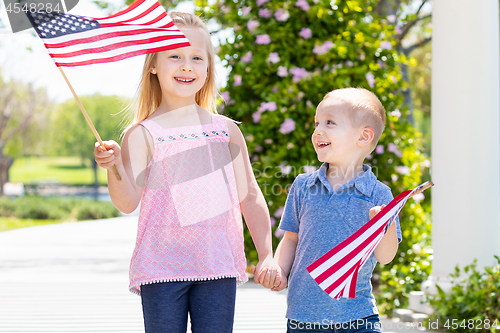 Image of Young Sister and Brother Waving American Flags At The Park