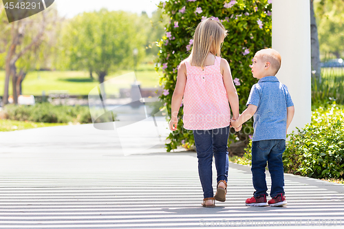 Image of Young Sister and Brother Holding Hands And Walking At The Park
