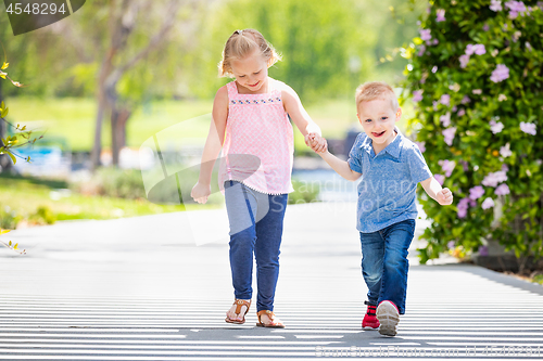 Image of Young Sister and Brother Holding Hands And Walking At The Park