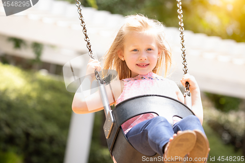 Image of Pretty Young Girl Having Fun On The Swings At The Playground
