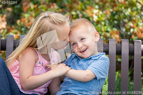 Image of Young Sister and Brother Having Fun On The Bench At The Park