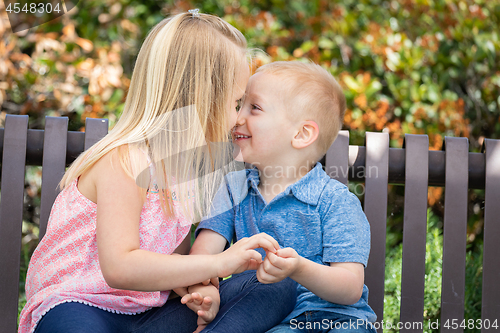 Image of Young Sister and Brother Having Fun On The Bench At The Park