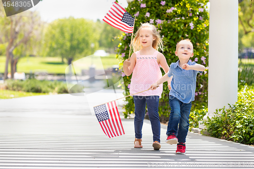 Image of Young Sister and Brother Waving American Flags At The Park