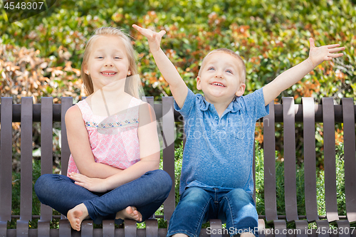 Image of Young Sister and Brother Having Fun On The Bench At The Park