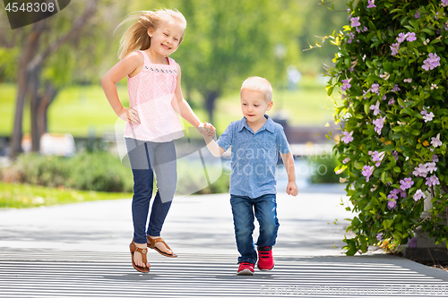 Image of Young Sister and Brother Holding Hands And Running At The Park