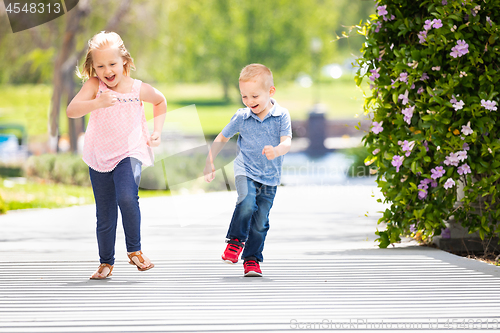 Image of Young Sister and Brother Having Fun Running At The Park