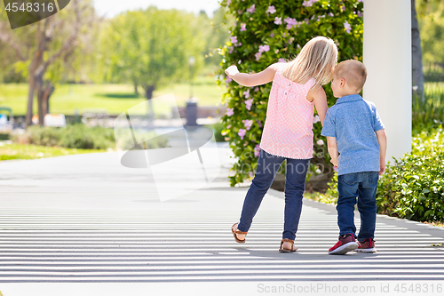 Image of Young Sister and Brother Holding Hands And Walking At The Park