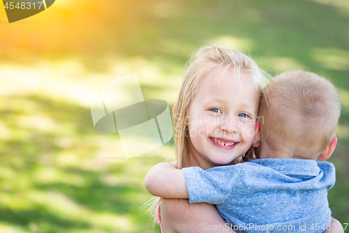 Image of Young Brother and Sister Hugging At The Park