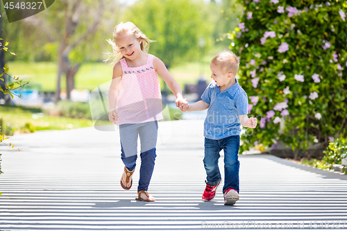 Image of Young Sister and Brother Holding Hands And Running At The Park