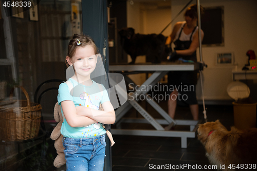 Image of little cute girl standing in front of beauty salon for animals