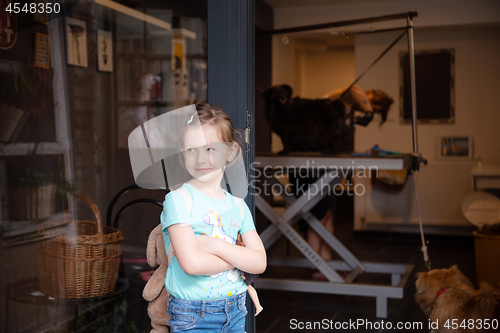 Image of little cute girl standing in front of beauty salon for animals