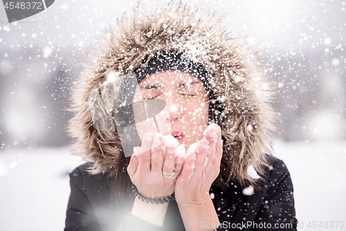 Image of young woman blowing snow on snowy day