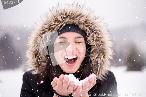 Image of young woman blowing snow on snowy day