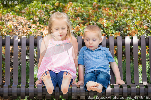 Image of Young Sister and Brother Having Fun On The Bench At The Park