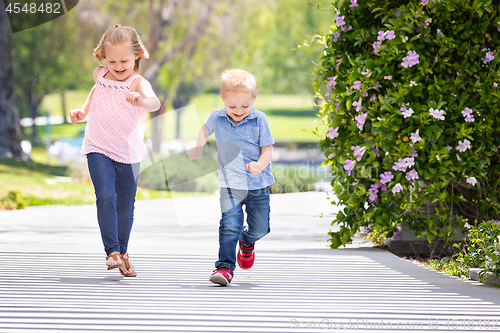 Image of Young Sister and Brother Having Fun Running At The Park