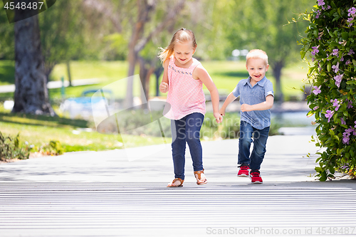 Image of Young Sister and Brother Having Fun Running At The Park