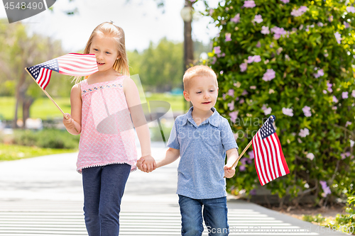 Image of Young Sister and Brother Waving American Flags At The Park