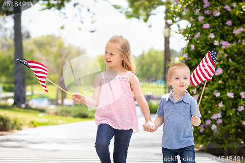 Image of Young Sister and Brother Waving American Flags At The Park